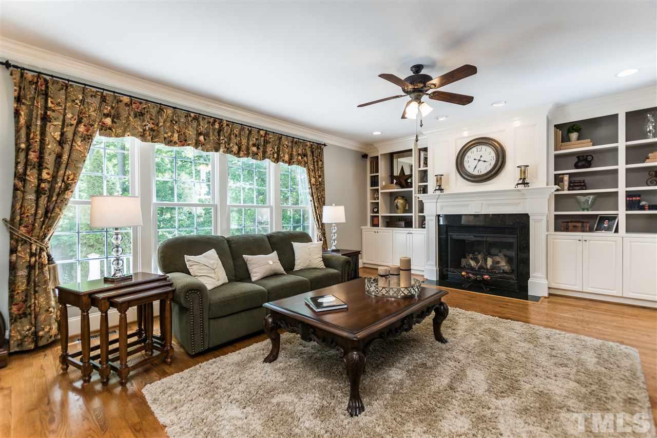 3413 Spartina Court Raleigh, NC 27606 - Photo 10 of 25 a living room with furniture a fireplace a clock and a large window