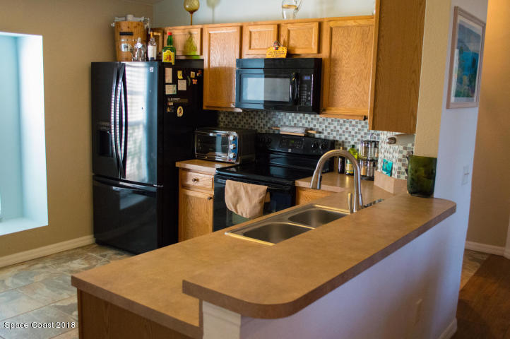 6130 Edison Street Cocoa, FL 32927 - Photo 10 of 15 a kitchen with stainless steel appliances granite countertop a refrigerator a stove and a sink with wooden floor
