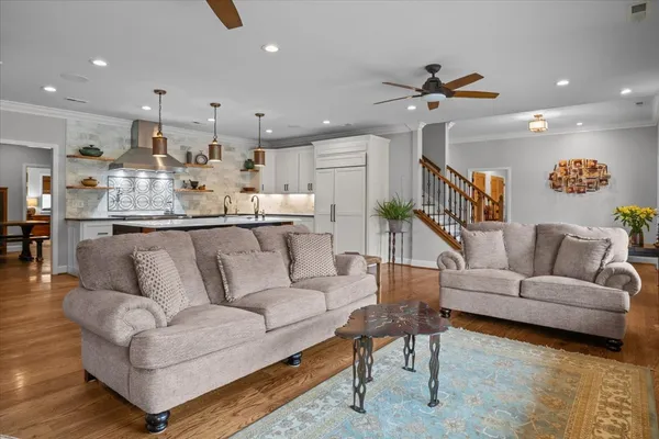 a living room with stainless steel appliances furniture a rug and a large window