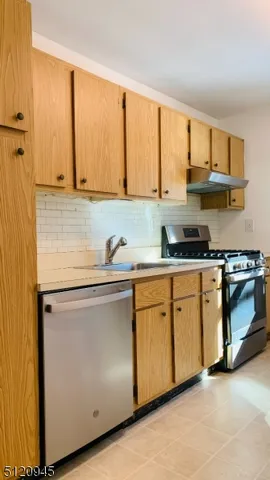 a kitchen with stainless steel appliances granite countertop a stove a sink and white cabinets