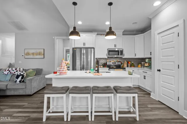 a kitchen with stainless steel appliances kitchen island granite countertop a table chairs refrigerator and microwave