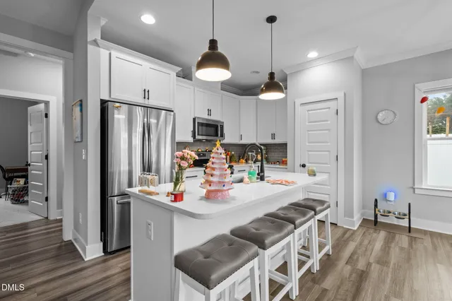 a kitchen with stainless steel appliances a refrigerator a stove a sink dishwasher a oven with a dining table and chairs with wooden floor