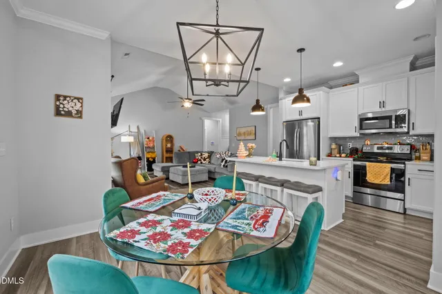 a living room with stainless steel appliances kitchen island granite countertop furniture a rug kitchen view and a chandelier