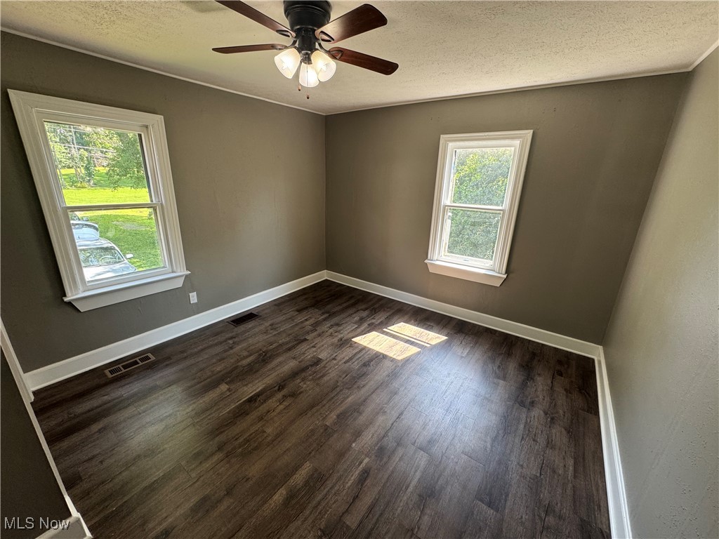 2660 Ridge Road Zanesville, OH 43701 - Photo 13 of 20 Unfurnished room featuring dark wood-style flooring, a textured ceiling, and a ceiling fan