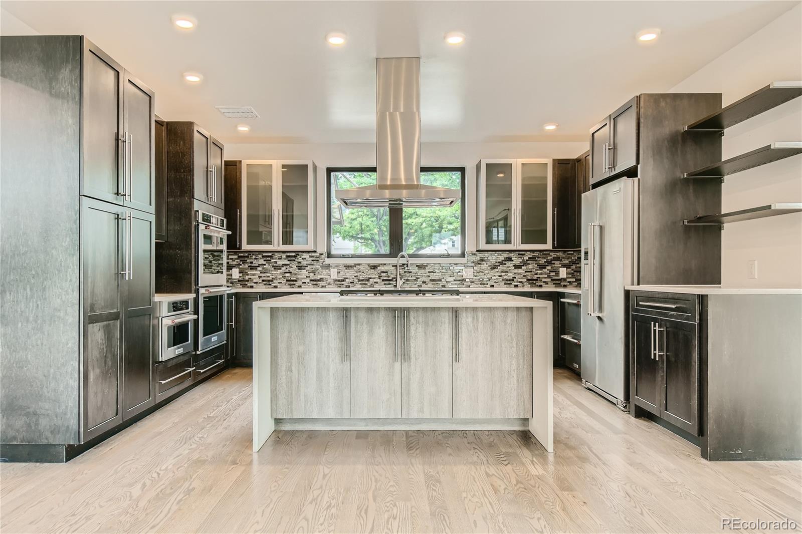 1609 Xavier Street Denver, CO 80204 - Photo 12 of 36 a kitchen with stainless steel appliances kitchen island granite countertop a refrigerator and a stove