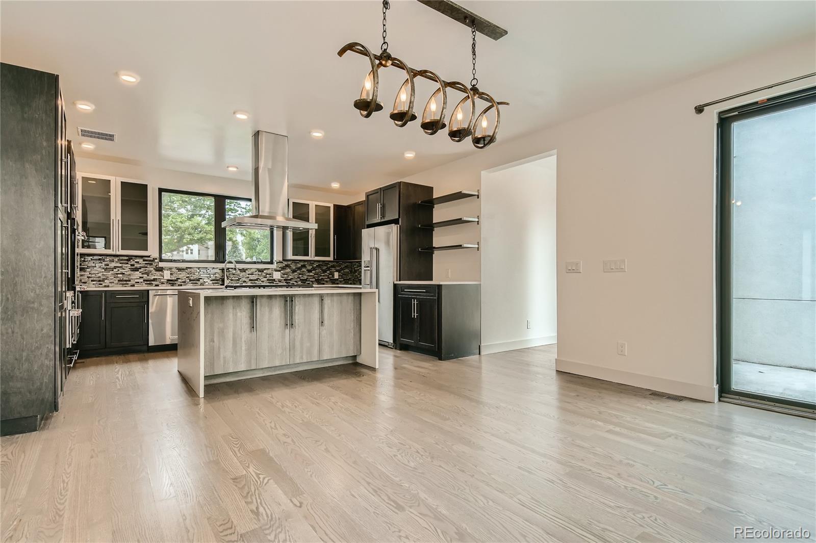 1609 Xavier Street Denver, CO 80204 - Photo 13 of 36 a large kitchen with stainless steel appliances kitchen island a large counter top and wooden floors
