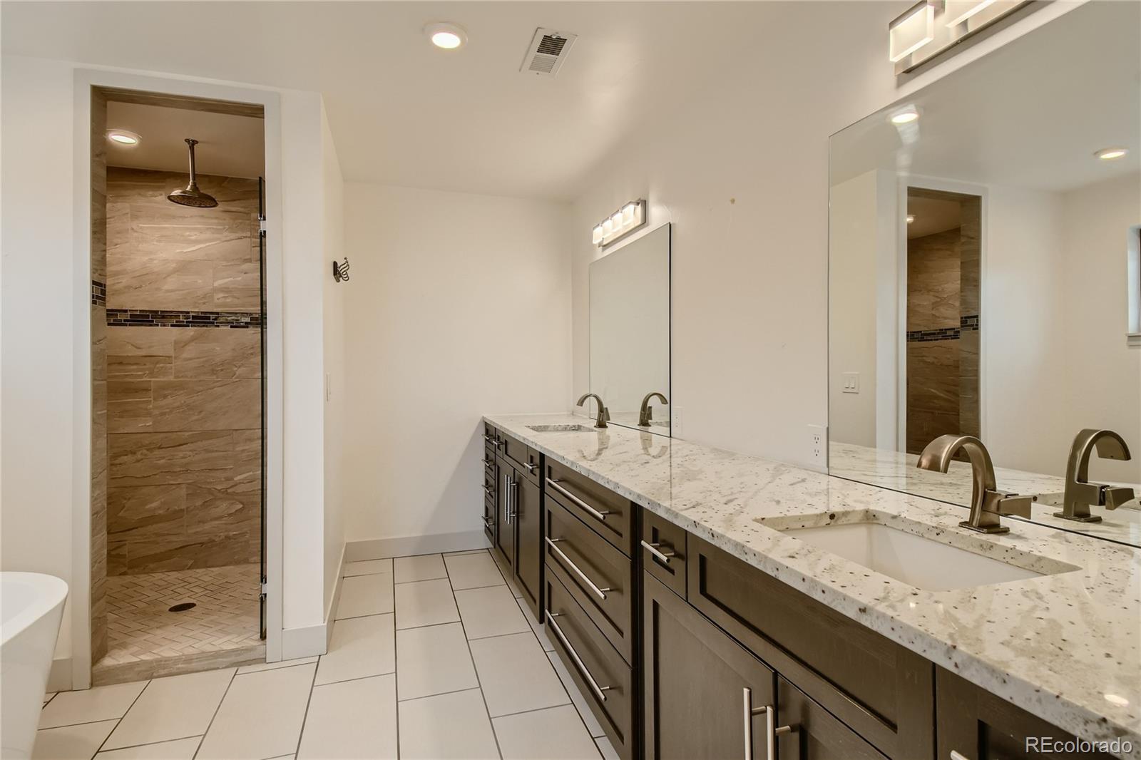 1609 Xavier Street Denver, CO 80204 - Photo 20 of 36 a bathroom with a granite countertop sink two mirror and shower