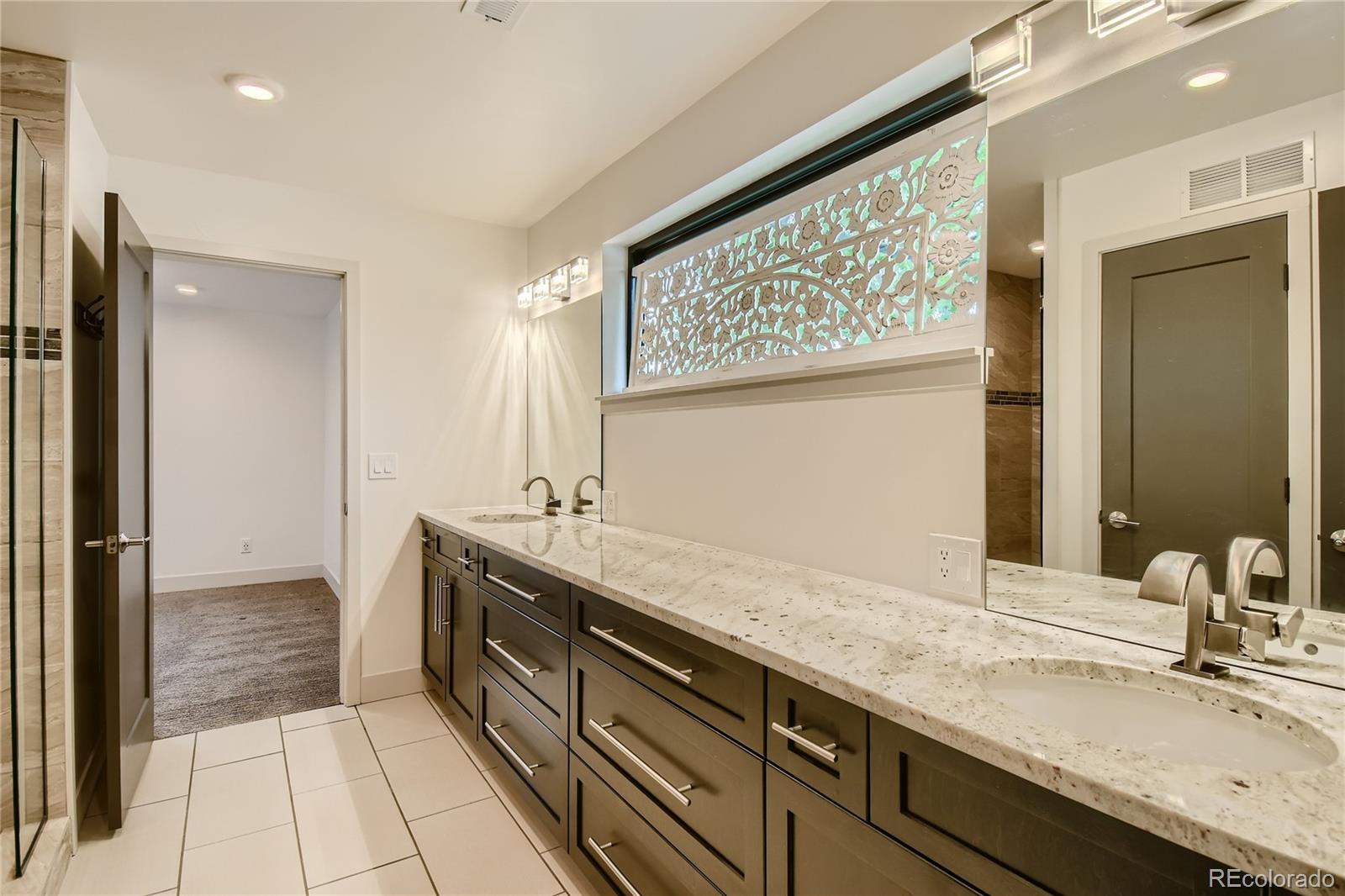 1609 Xavier Street Denver, CO 80204 - Photo 23 of 36 a spacious bathroom with a granite countertop sink and a mirror