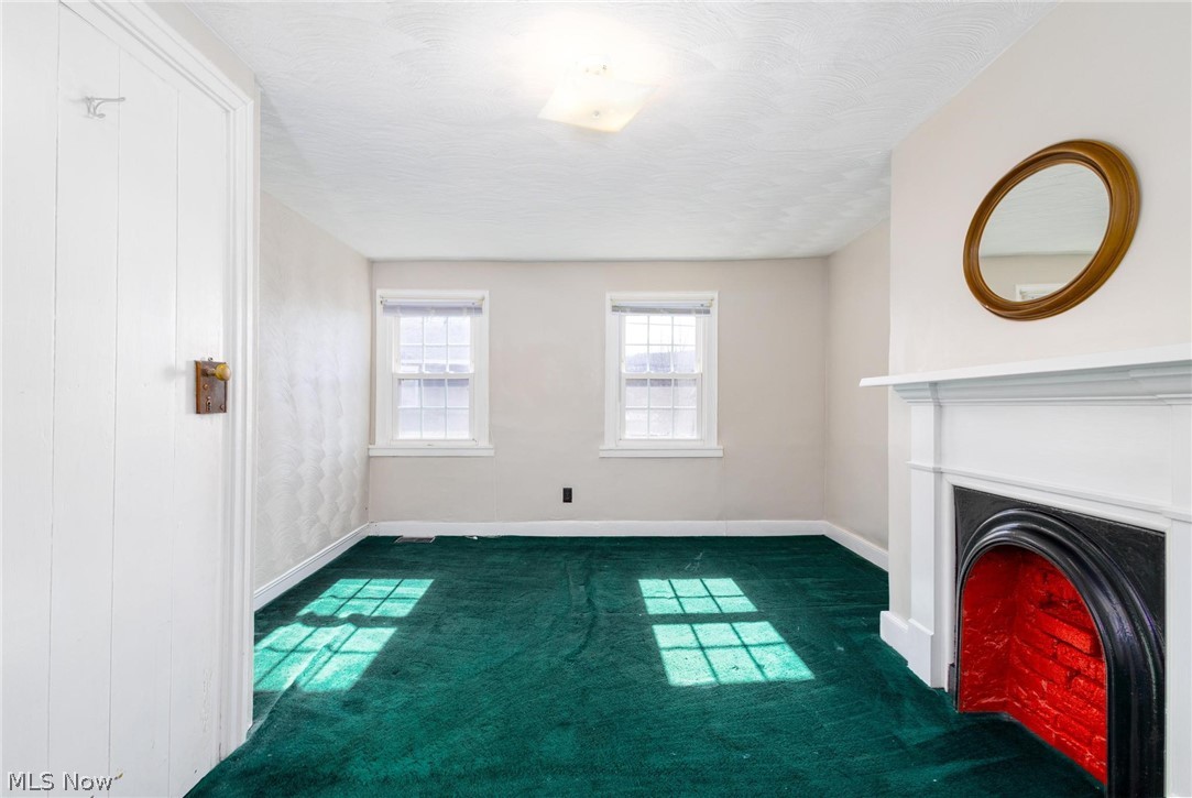 165 9th Street Wellsburg, WV 26070 - Photo 29 of 37 Unfurnished living room with dark colored carpet, a lit fireplace, and a textured ceiling