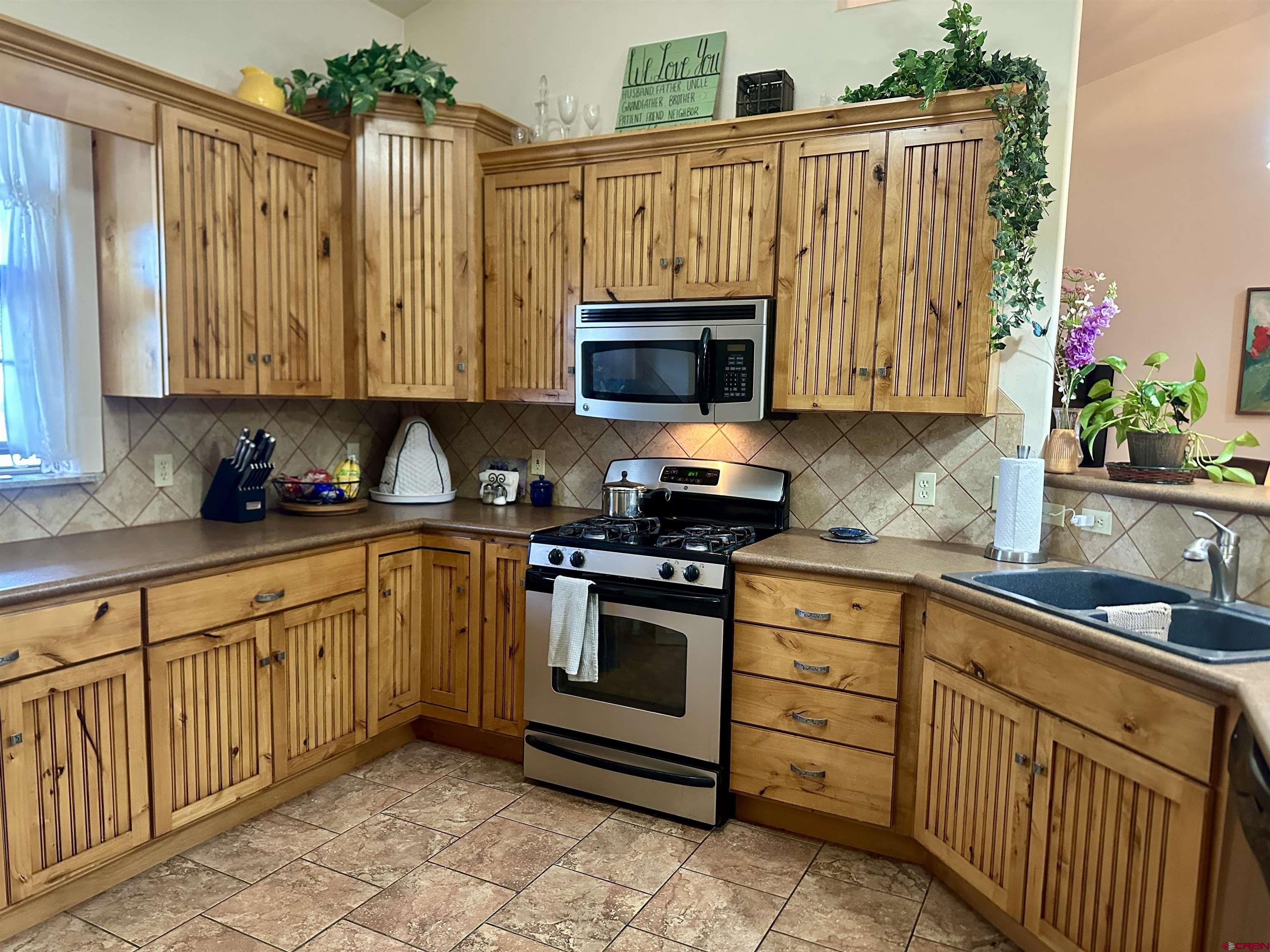 515 Southeast 2nd Street Cedaredge, CO 81413 - Photo 12 of 35 a kitchen with granite countertop a sink a stove a microwave and cabinets