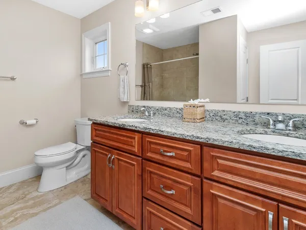 a bathroom with a granite countertop sink a toilet and a mirror