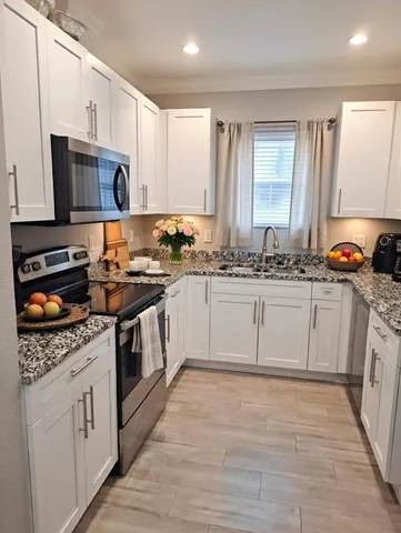 a kitchen with stainless steel appliances granite countertop a sink stove a microwave oven a refrigerator with white cabinets