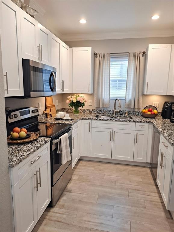 a kitchen with stainless steel appliances granite countertop a sink stove a microwave oven a refrigerator with white cabinets