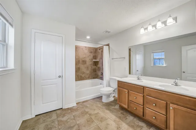 a bathroom with a double vanity sink a toilet a bathtub and shower