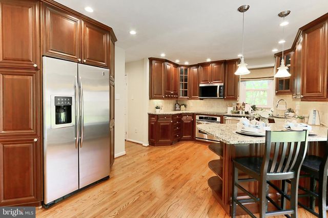 a kitchen with stainless steel appliances kitchen island granite countertop a refrigerator a stove a sink dishwasher and a dining table with wooden floor