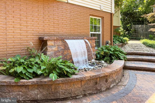 a front view of a house with a fountain and a tree