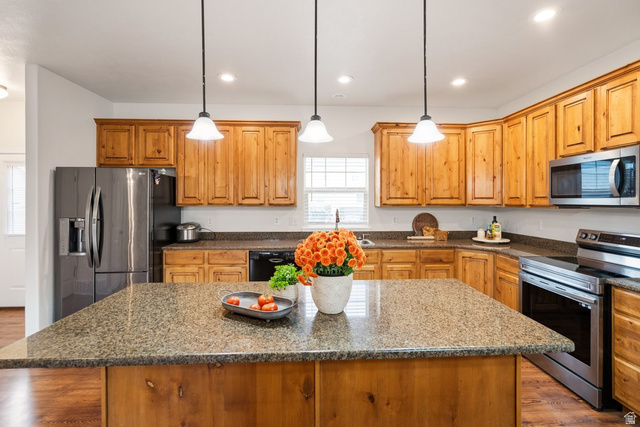 2029 West Crescent Row Mapleton, UT 84664 - Photo 14 of 35 Kitchen featuring an island with a stone-finish countertop, wood-finish cabinetry, stainless steel appliances, and pendant lighting