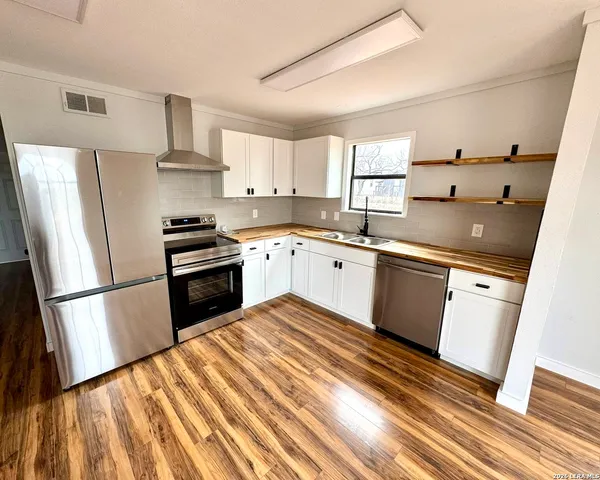 a kitchen with a sink a refrigerator and wooden floor