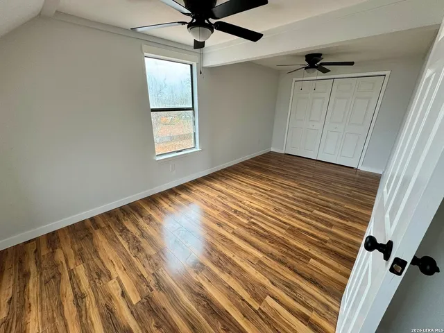 a view of empty room with wooden floor and fan