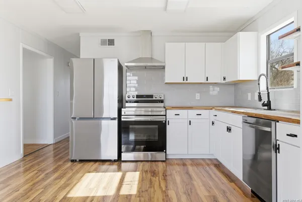 a kitchen with white cabinets stainless steel appliances and wooden floor