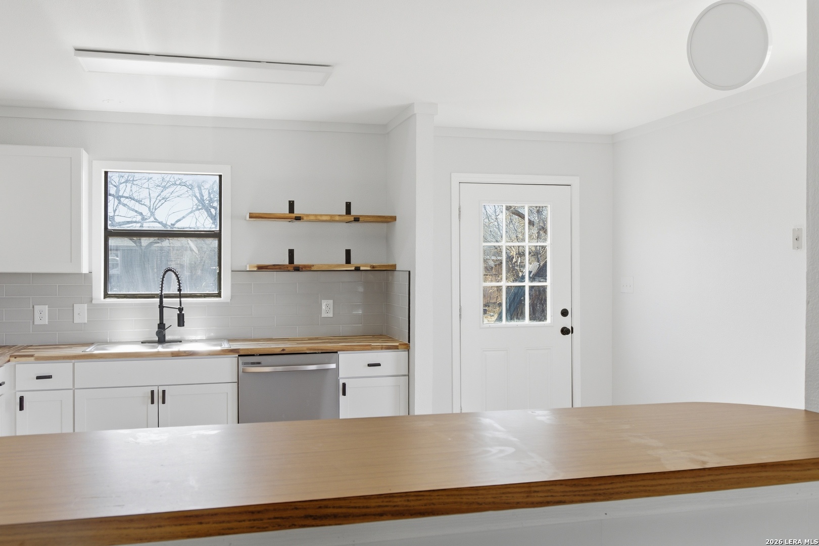 910 Cypress Street Jourdanton, TX 78026 - Photo 9 of 25 a large white kitchen with kitchen island a sink stainless steel appliances and cabinets