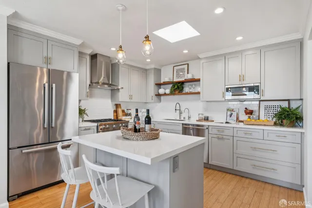 a kitchen with a refrigerator a stove a sink and white cabinets with wooden floor