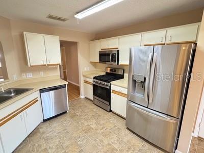 9759 Southwest 97th Lane Ocala, FL 34481 - Photo 14 of 28 a kitchen with stainless steel appliances a refrigerator a stove a sink cabinets and a refrigerator