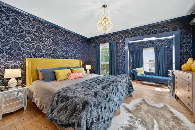 a bedroom with a bed and a large mirror on dresser with wooden floor