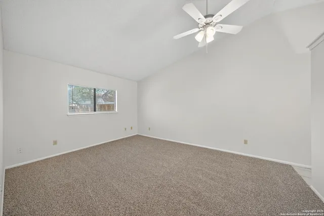an empty room with a window and a ceiling fan