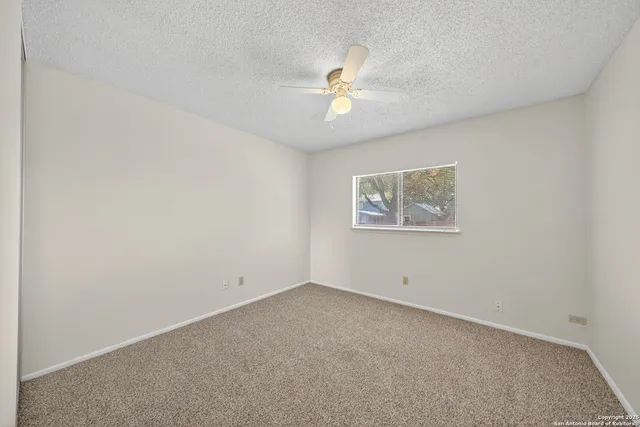 an empty room with a fan & a window