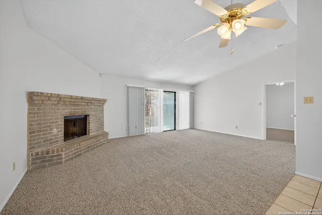 a view of a livingroom with a fireplace and a chandelier fan