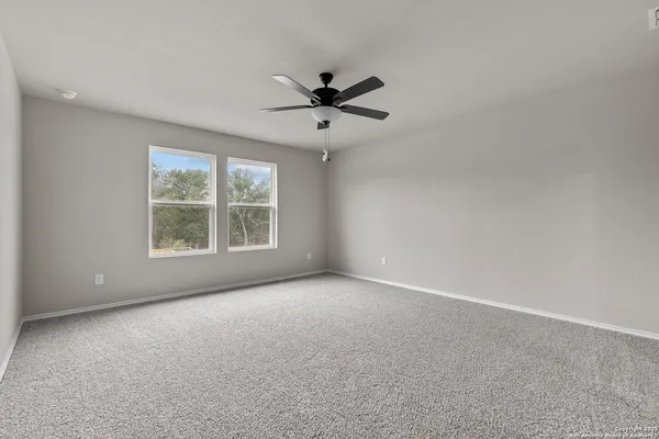 an empty room with windows and ceiling fan view