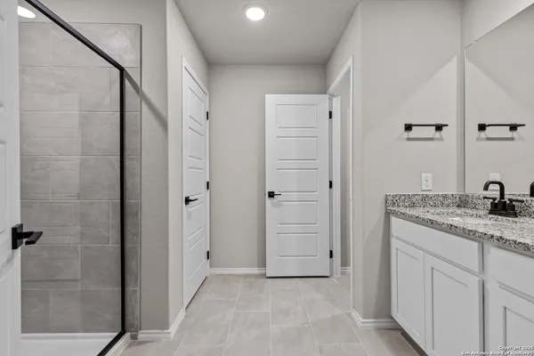 a bathroom with a granite countertop sink two mirror and shower