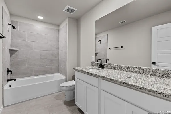 a bathroom with a granite countertop sink a toilet and bathtub