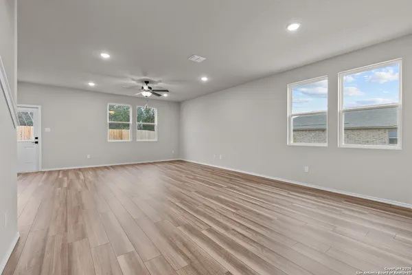 an empty room with wooden floor and windows