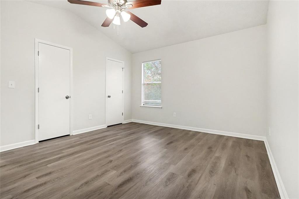 5474 Panola Downs Road Lithonia, GA 30058 - Photo 13 of 27 an empty room with wooden floor chandelier fan and windows