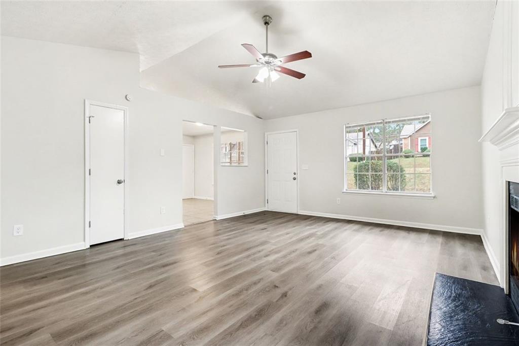 5474 Panola Downs Road Lithonia, GA 30058 - Photo 7 of 27 an empty room with wooden floor chandelier fan and windows