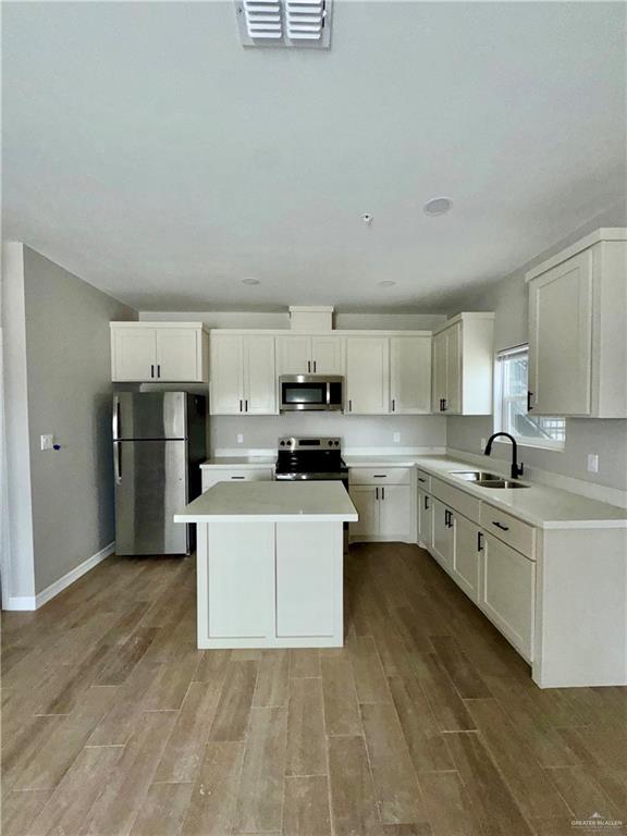 720 Ragland Road, Unit 2 Mission, TX 78572 - Photo 5 of 8 a large white kitchen with stainless steel appliances granite countertop a stove a sink a refrigerator white cabinets and wooden floor