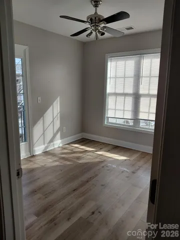 a view of empty room with wooden floor and fan