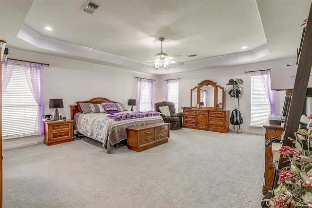 a spacious bedroom with a bed a couch and dresser