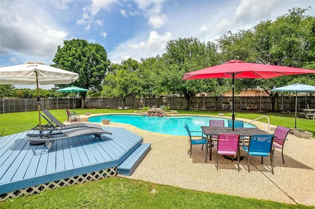 a view of swimming pool with seating area and trees in the background