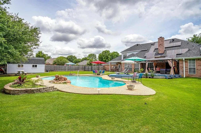 a view of a swimming pool with lawn chairs and a big yard
