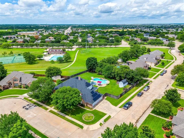 an aerial view of a residential houses with outdoor space and trees all around