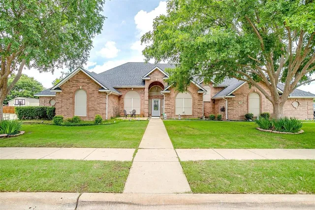 a view of a yard in front of a house with plants and large tree