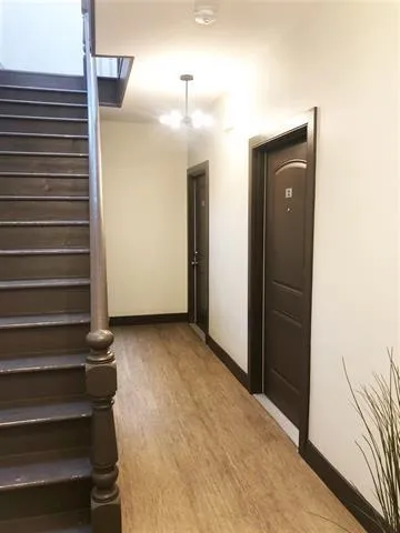 a view of a hallway with stairs and wooden floor