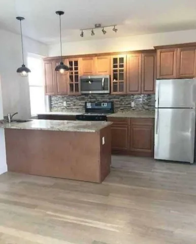 a kitchen with stainless steel appliances granite countertop a sink and a refrigerator