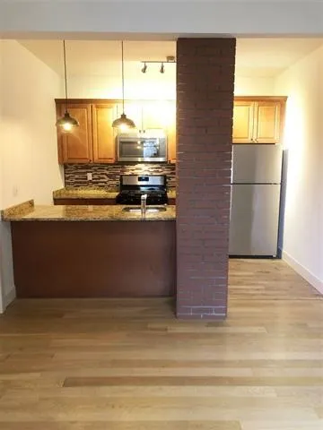 a view of kitchen with stainless steel appliances granite countertop cabinets and a floor to ceiling window