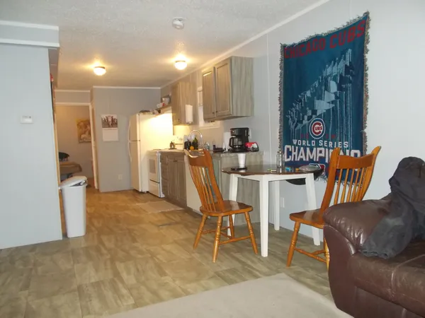 a kitchen with stainless steel appliances kitchen island granite countertop a refrigerator a stove a dining table and chairs