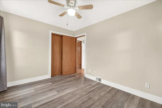 an empty room with wooden floor and fan