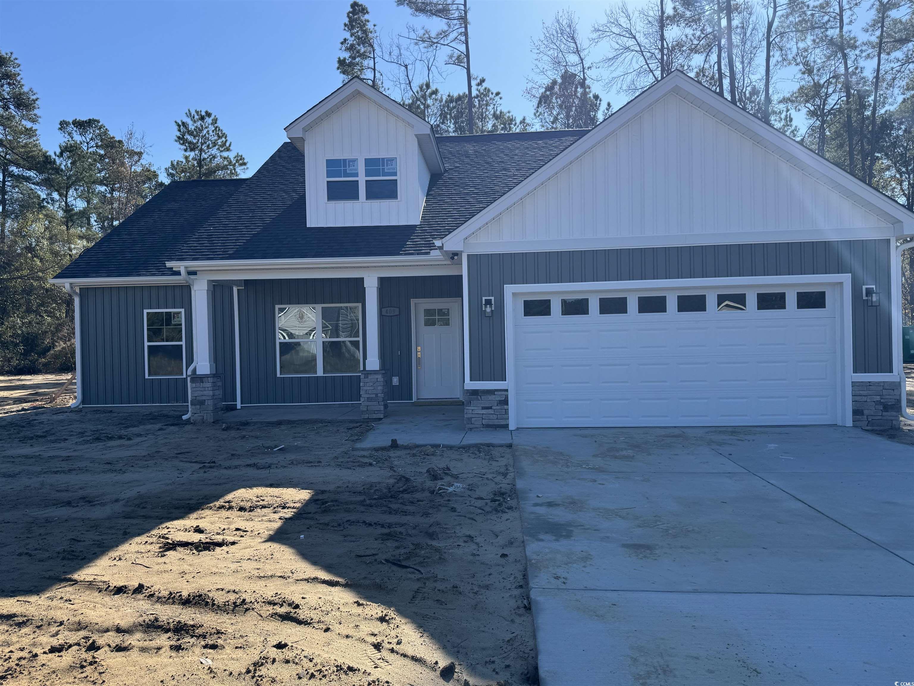 View of front of property with a porch, roof with shingles, concrete driveway, and stone siding
